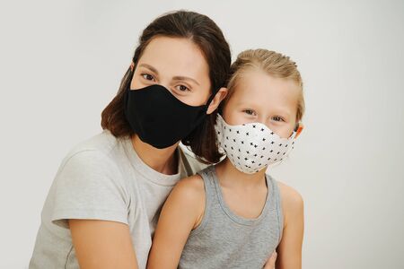 portrait of mother and son in protective masks against a white background