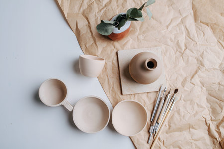 Pottery ceramic products of blank beige color. Fired and polished. Bowls, cups and vase. Top view.