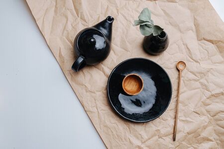 Pottery ceramic products of black color. Fired, polished, dyed black and varnished. Bowl, tea pot and vase along with some wooden tableware. Top view.の写真素材