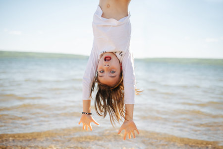 Little hiperemotional school age girl hanging upside down, having fun, thrilled scared a bit. On a...