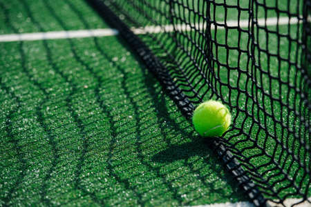 Tennis lying on the lower part of the net on a green court. Net casting shadow on a cover.の写真素材