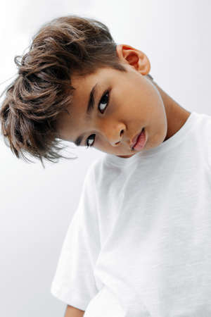 Rigid indian asian kid with head tilted to side and downの写真素材