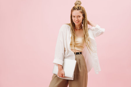 Stunning eccentric young woman with stylish blond afro braids over pink background. She's posing for...