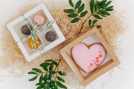 Composition of christmas sweets and big scarlet shaped cookie in windowed boxes on a pile of filling paper with rowan branches sticking out. top viewの写真素材