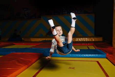 Clumsy little boy jumping on a square trampoline in entertainment centerの写真素材