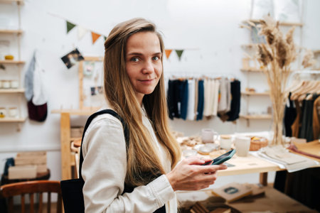 Portrait of a young woman standing in an ecological shop with a phone in handの写真素材