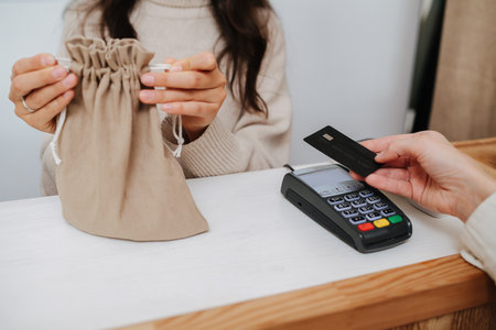 Cropped image of shopkeeper putting goods in a fabric bag for a paying customerの写真素材