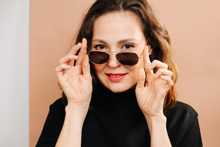Portrait of a nice woman with makeup holding on to sunglassesの写真素材
