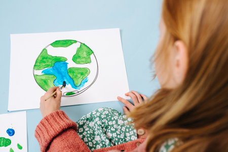 An environmental concept. Girl paints a picture of green landの写真素材