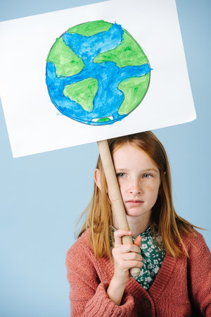 Sad red-haired girl eco activist with poster green landの写真素材