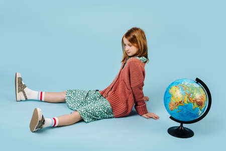 Red hair girl and globe on a blue background