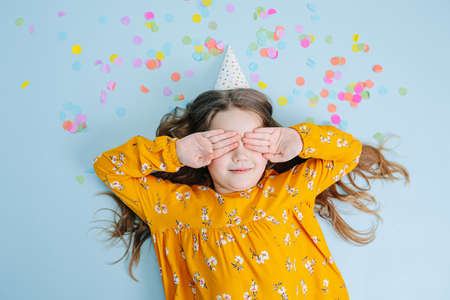 Birthday girl lies on a floor covering eyes with handsの写真素材