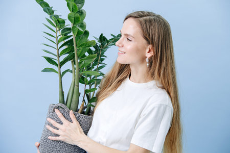 Happy woman standing with a plant in a wicker potの写真素材