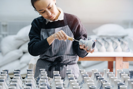 Keen woman filing freshly cast vases, removing unnessesary bits, finishing themの写真素材