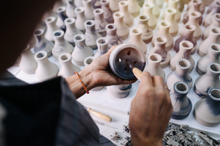 Woman filing freshly cast vases, removing unnessesary bits, finishing them