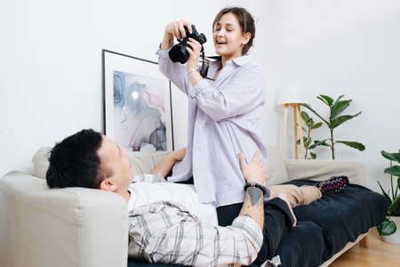 Couple spends time together on a sofa, a girl takes picturesの写真素材