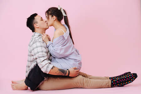 Young couple hugs and kissing on a pink backgroundの写真素材