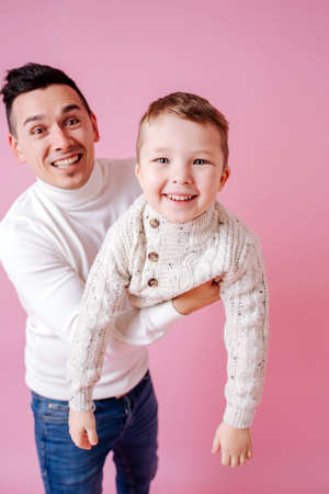 Happy euphoric dad bringing up cheerful son close to the camera, posingの写真素材