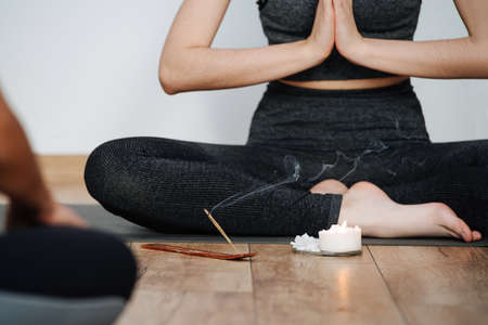Cropped image of female instructor practicing yoga, meditating with joined handsの写真素材
