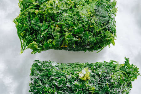 Cropped frozen parsley green briquettes on a grinded ice. top view.の写真素材