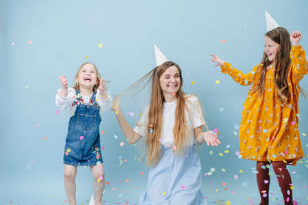 Daughters hugging their mother, all in party cones over blueの写真素材