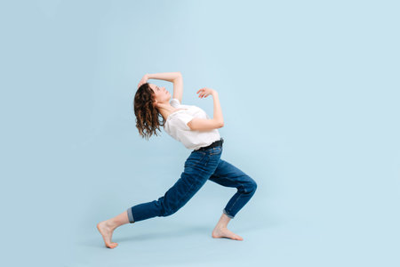 Flexible contemporary dancer in a lunge, arching herself back. In a studio.の写真素材
