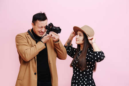 He looks into the viewfinder of the camera, a young girl in a hat poses for him.の写真素材