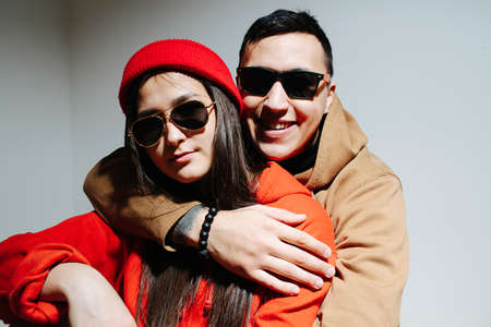 A man hugs a woman, they are wearing sunglasses sitting on the floorの写真素材