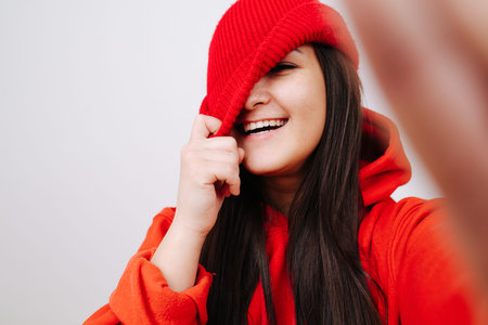 Portrait of a laughing girl holding her hat, dressed in all red