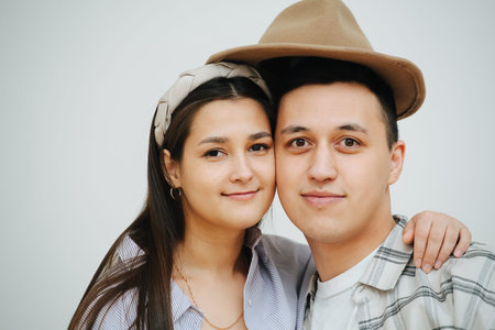 A man and a woman under the same hat, hugging and posing