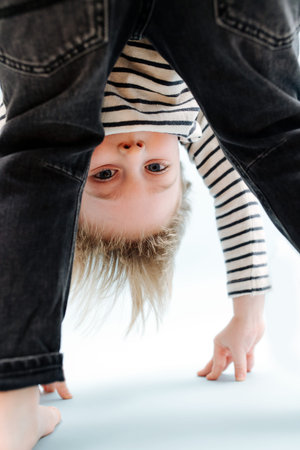 Silly little blond boy bending forward, looking between his legs. Over blueの写真素材