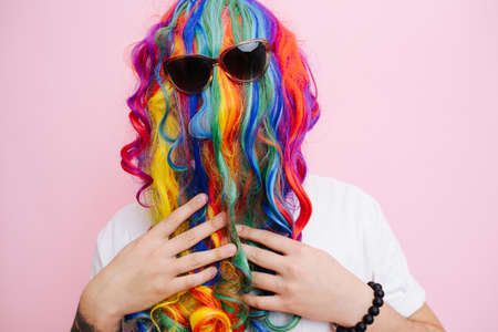 Extremely funny looking man in a wig over face, worn back to front and sunglasses over it. He is...