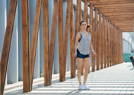 Heavily exercising brunette skipping outdoors under a wooden frame tunnelの写真素材