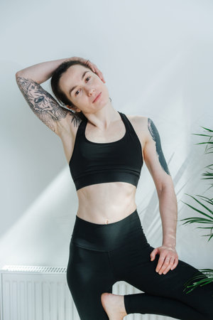 Portrait of young woman with shoulder tattoos posing in a yoga sportswear