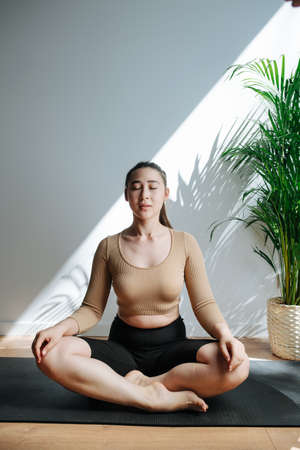 Serene woman practicing yoga, meditating with her eyes closed. Frontal view