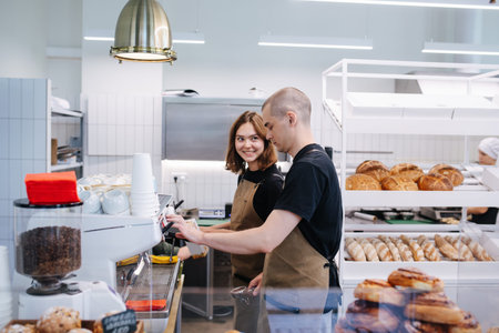 Coworkers, young man and woman socialising in the bakery kitchen. Side view. She's smiling at him.の写真素材