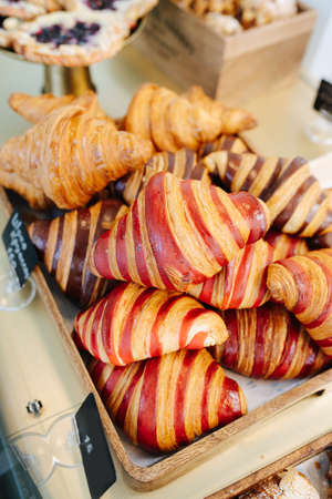 Vibrant striped croissant in a pile on a tray. Red, chocolate and regular ones.の写真素材