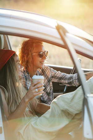 Two girl friends sitting in the car, enjoying views of steppe, smilingの写真素材