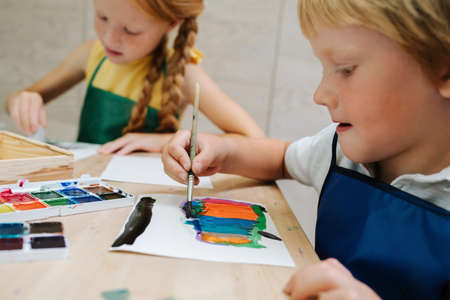 Immersed kids painting with watercolor. Low angle.の写真素材