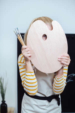 Shy teacher hiding behind a wooden palette, looking in the hole in itの写真素材