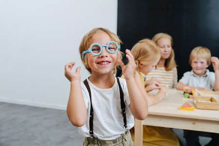 Little boy playing with blue plastic toy glasses, radiantly smiling.