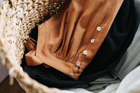 Close up image of a wicker basket full with summer dresses for washing laungry. Top view.
