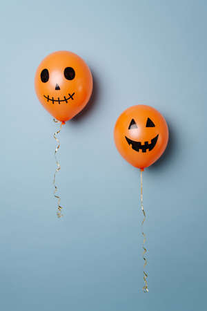 Halloween orange balloons with carved pumpkin inspired grimaces. Over blue background.の写真素材