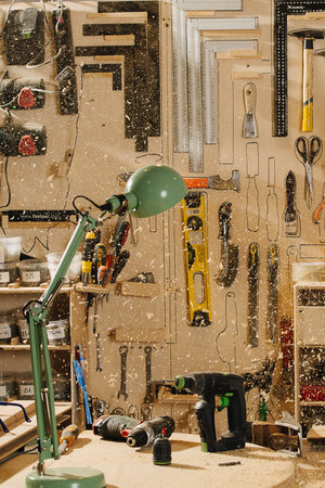 Carpentry workshop, saw shavings are flying everywhere. Empty workplace Number of tools hanging on the wall.の写真素材