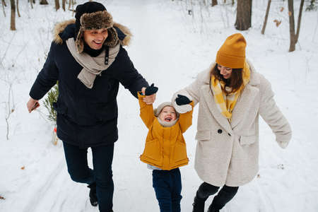 The family has fun walking through the winter forest on Christmas Eveの写真素材