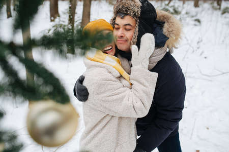 Loving couple in winter, they hug standing behind a Christmas treeの写真素材