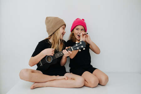 Little siblings playing with musical instrumets, having fun, pretending. They are fearing colorful knitted hats.の写真素材