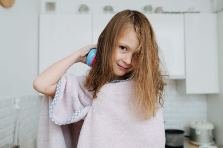 Pretty little girl wrapped in a towel sticking tongue out. She's looking at the camera, she brushed one side, other side covering half of her face.の写真素材