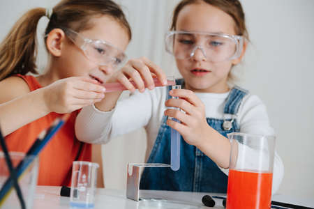 Happy little girls doing science project, they are mixing two colored liquidsの写真素材