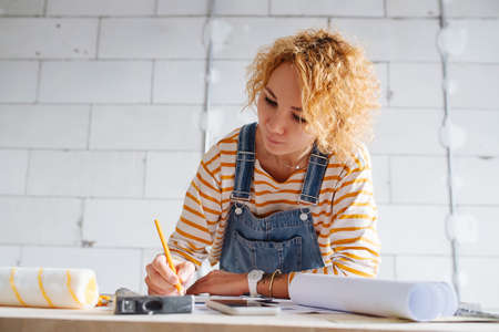 Low angle image of a female construction engineer working on a blueprint. Over a rough gray brick wall.の写真素材